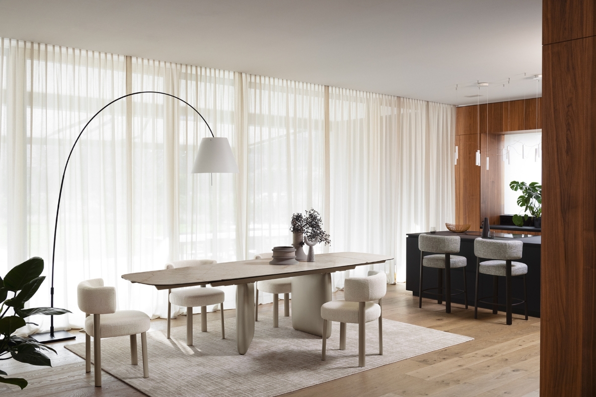 Τραπέζι τραπεζαρίας οβάλ Calligaris Riverstone επεκτεινόμενο με cream κεραμική και εκρού λακαριστή ασύμμετρη βάση σε φωτεινό χώρο — Adamopoulos Casa Ideale