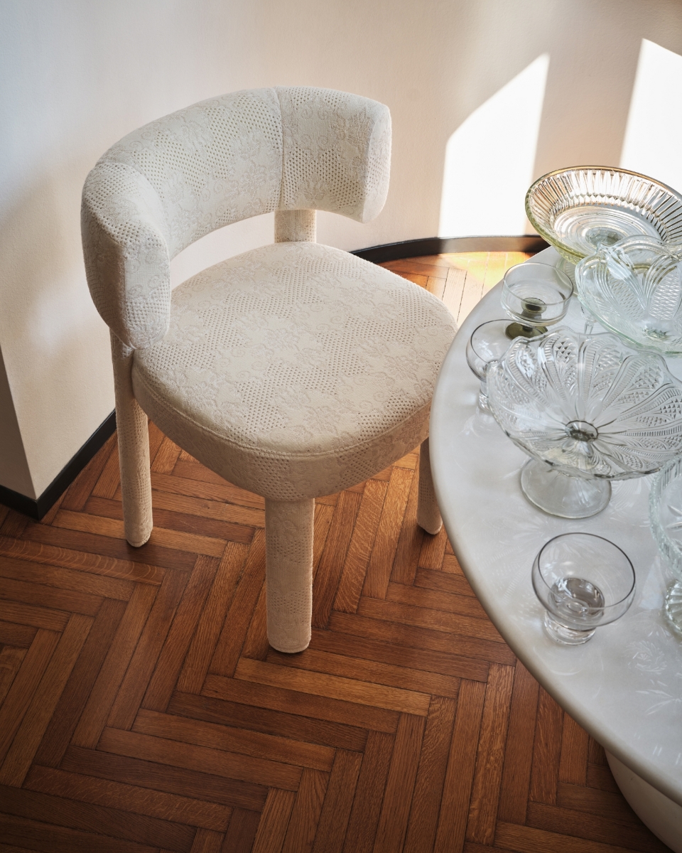 Καρέκλα Calligaris Glen Soft Twinset ντυμένη με εκρού δαντελωτό ύφασμα, δίπλα σε λευκό στρογγυλό μαρμάρινο τραπέζι με κρύσταλλα, σε ξύλινο πάτωμα ψαροκόκαλο