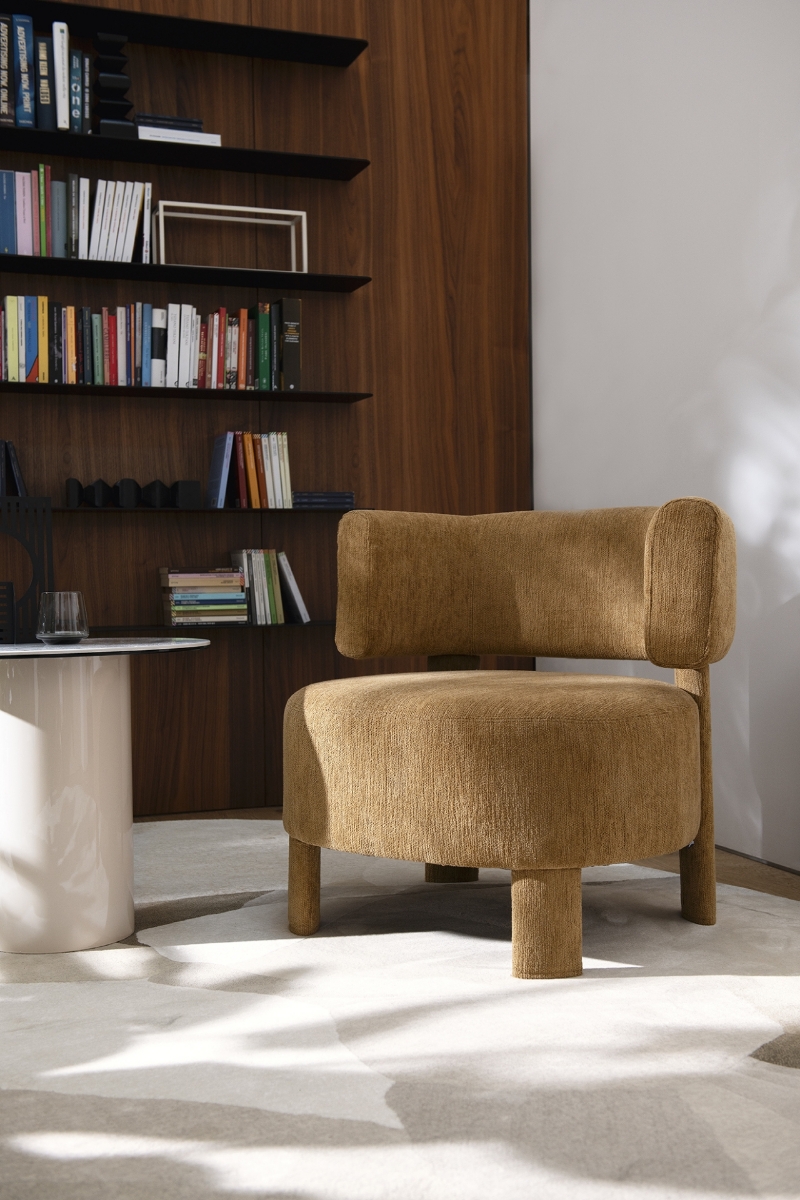Καμηλό πολυθρόνα Calligaris Glen Soft ολόντυτη με ύφασμα σε φωτεινό σαλόνι με ξύλινη βιβλιοθήκη και μαρμάρινο τραπεζάκι, μπροστινή όψη με φυσικό φως