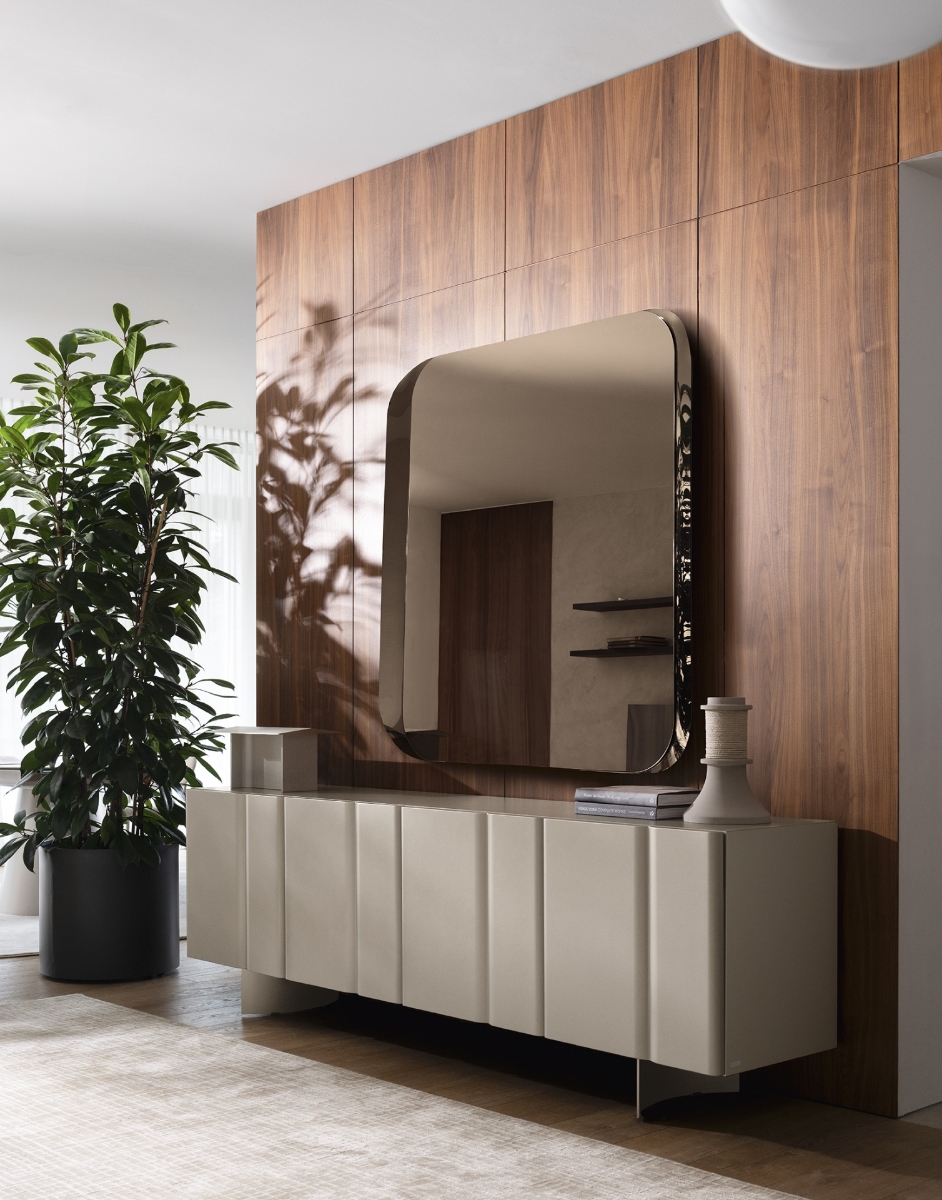 Τετράγωνος καθρέπτης τοίχου Calligaris Divine σε μπρονζέ απόχρωση με στρογγυλεμένες γωνίες, πάνω σε ξύλινο τοίχο καρυδιάς με μπεζ μπουφέ και πράσινο φυτό — Adamopoulos Casa Ideale, επίσημος αντιπρόσωπος Calligaris στην Ελλάδα