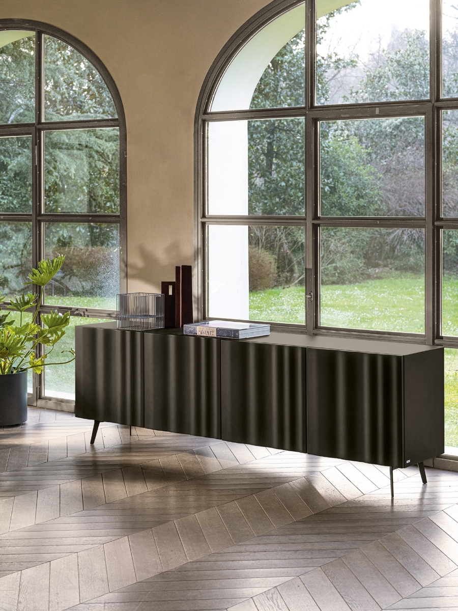 Μπουφές Calligaris Velo σε καφέ μόκα απόχρωση με ανάγλυφες πόρτες-πέπλο και λεπτά μεταλλικά πόδια, μπροστά από τοξωτά μεταλλικά παράθυρα με θέα σε κήπο — Adamopoulos Casa Ideale, επίσημος αντιπρόσωπος Calligaris στην Ελλάδα